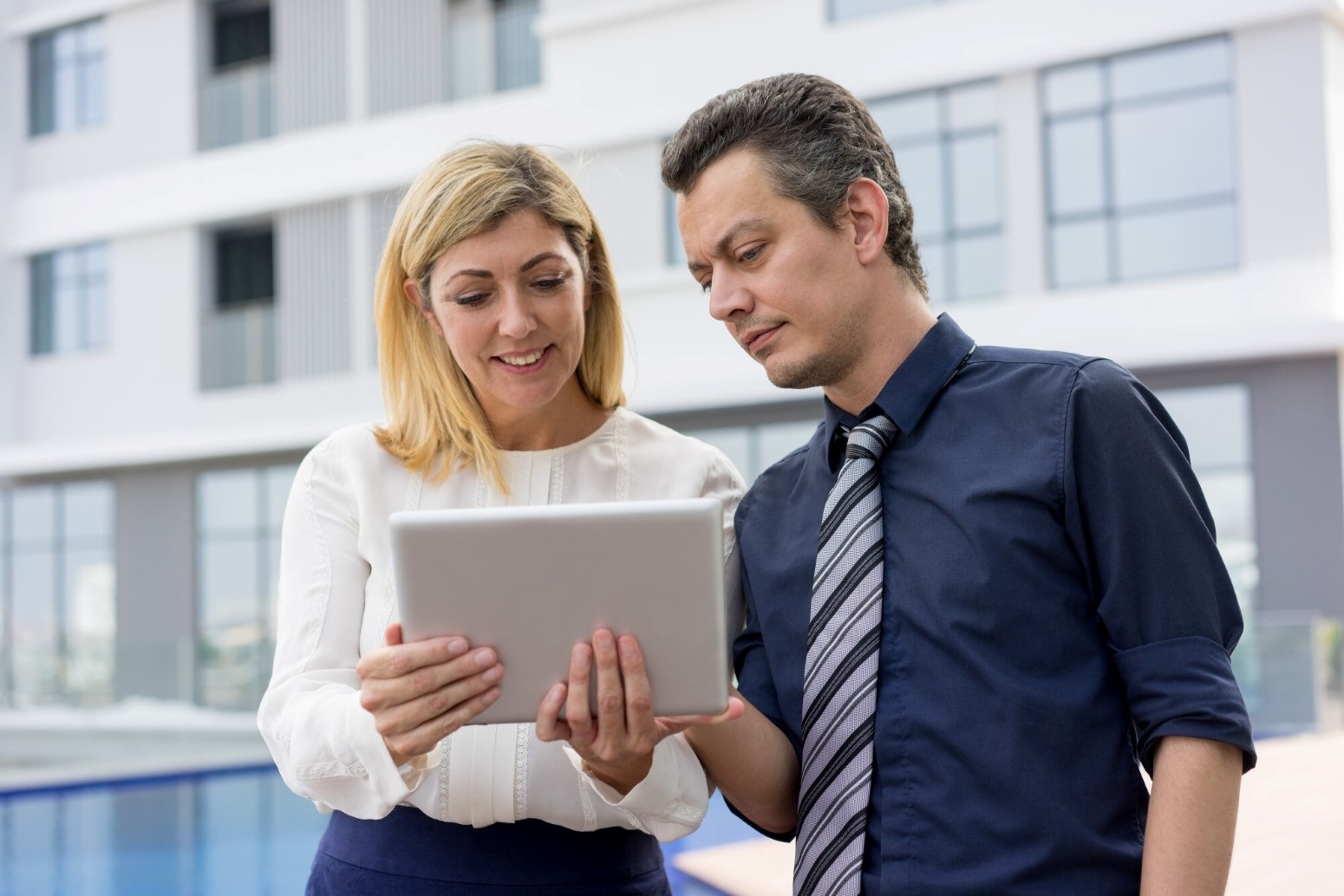 Commercial Property Management Lexington KY 1 - The Gibson Company Two colleagues review a tablet together outdoors near a modern office building.